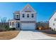 Two-story home with a covered porch, two-car garage, and a well-manicured lawn at 90 Rigsby Ave, Four Oaks, NC 27524