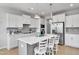 Bright kitchen features white cabinets, stainless steel appliances and island with bar stool seating at 90 Rigsby Ave, Four Oaks, NC 27524