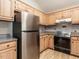 Bright kitchen with stainless steel refrigerator, light wood cabinets and granite countertops at 916 Belhaven Rd, Cary, NC 27513