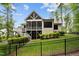 Landscaped backyard with green lawn, stairs leading to a screened porch, and a black fence at 946 Berry Patch Ln, Pittsboro, NC 27312