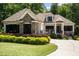 Charming home exterior featuring stone accents, black shutters, a well-manicured lawn, and beautiful landscaping at 946 Berry Patch Ln, Pittsboro, NC 27312