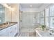 Elegant bathroom featuring a glass-enclosed shower and a soaking tub with stylish fixtures at 1012 Addison Pl, Raleigh, NC 27610