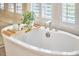 Relaxing bathroom featuring a modern soaking tub with a plant accent and window shutters for privacy at 1012 Addison Pl, Raleigh, NC 27610