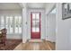 Bright foyer with hardwood floors, a red front door, white trim, and a view of the dining room at 1012 Addison Pl, Raleigh, NC 27610