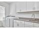 Bright laundry room with white cabinets, gray countertops, and modern washer and dryer at 1016 Addison Pl, Raleigh, NC 27610