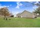 View of a large backyard with green grass, a fire pit, and a house with neutral siding under a partly cloudy sky at 112 E Main St, Micro, NC 27555