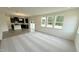 Open-concept living space showcasing natural light, a modern kitchen with dark cabinets, and carpeted floors at 140 Gobbler Dr, Smithfield, NC 27577