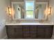 Bathroom with double vanity, marble countertop, custom cabinets, and a large mirror at 1405 Song Bird Crest Way, Raleigh, NC 27613