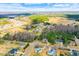 Expansive aerial view of a neighborhood surrounded by lush green spaces and mature trees under a bright blue sky at 153 Dell Meadows Pl, Four Oaks, NC 27524