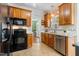 Functional kitchen with wooden cabinets, black appliances, and a view into the adjacent dining area at 153 Dell Meadows Pl, Four Oaks, NC 27524