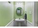 Compact powder room with a pedestal sink, decorative mirror, and green walls, perfect for guests' convenience at 153 Dell Meadows Pl, Four Oaks, NC 27524