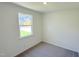 Minimalist bedroom with neutral walls and plush carpet featuring a window with a view of the neighborhood and natural light at 158 Gobbler Dr, Smithfield, NC 27577