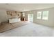 Open-concept living area and kitchen featuring unfinished cabinets and island, sliding glass door, and large windows at 158 Gobbler Dr, Smithfield, NC 27577