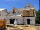 New home under construction showcasing the architectural framing and protective wrap on a sunny day at 197 W Saltgrass Ln, Smithfield, NC 27577