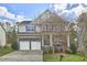 Inviting two-story home with stone accents, a two-car garage, and a well-manicured lawn, offering charm and curb appeal at 215 Strolling Way, Durham, NC 27707