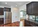 Modern kitchen boasts stainless steel refrigerator, dark cabinets, granite countertop and tile backsplash at 215 Strolling Way, Durham, NC 27707