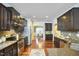 Bright, open kitchen with stainless steel appliances, dark cabinetry, granite countertops, and hardwood floors at 215 Strolling Way, Durham, NC 27707