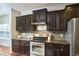Stylish kitchen featuring dark cabinets, granite counters, stainless appliances, and natural light at 215 Strolling Way, Durham, NC 27707