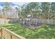 Backyard featuring a wooden fence, lush green grass, and a charming wooden playset, perfect for outdoor adventures at 215 Strolling Way, Durham, NC 27707