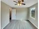 Bedroom features light walls, modern gray floors, a ceiling fan, a window view, and a closet at 2412 Little John Rd, Raleigh, NC 27610