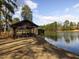 Scenic lake view featuring a picnic pavilion, a serene lake, and lush trees under a sunny sky at 2459 Memory Ridge Dr, Raleigh, NC 27606