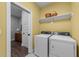 This laundry room features a washer and dryer set, a shelf with baskets, and access to another room at 2500 Plowridge Rd, Fuquay Varina, NC 27526