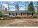 Charming one-story brick home featuring black shutters, manicured landscaping, and a cozy front porch at 303 Granville Rd, Chapel Hill, NC 27514