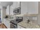 A well-lit kitchen features white cabinets, granite countertops, a stainless steel microwave and tile backsplash at 330 Bridgeport Cir, Clayton, NC 27527