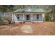 Charming single-story home featuring a covered front porch, set against a backdrop of mature trees at 404 Cherry St, Oxford, NC 27565