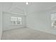 Spacious bedroom featuring tray ceilings, two windows offering natural light, and neutral carpeting at 4821 Heathshire Dr, Raleigh, NC 27616
