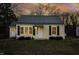Charming home with green shutters and matching metal roof, set against a dramatic sunset backdrop at 510 Short W St, Hillsborough, NC 27278