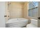 Bright bathroom featuring a soaking tub with shower head and tile surround at 706 Collington Dr, Cary, NC 27511