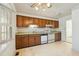 Functional kitchen with wooden cabinets, white appliances, and floral wallpaper at 706 Collington Dr, Cary, NC 27511