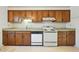 Kitchen with wooden cabinets, white appliances, and floral wallpaper and laminate countertops at 706 Collington Dr, Cary, NC 27511