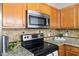 Close up of the kitchen showing the stove, granite countertop, and stainless steel microwave at 723 Renshaw Ct, Cary, NC 27518