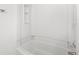 Clean bathtub featuring bright white tiling and functional shelving at 7317 Sandy Creek Dr, Raleigh, NC 27615