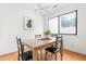 Sunlit dining area with wood table, black chairs, modern lighting, and large window view at 7317 Sandy Creek Dr, Raleigh, NC 27615