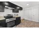 Modern kitchen with black cabinetry, stainless steel appliances, and tile flooring at 7317 Sandy Creek Dr, Raleigh, NC 27615
