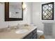 Bathroom featuring tan walls, a black-framed mirror, vanity, window, and toilet at 7904 Kingsland Dr, Raleigh, NC 27613
