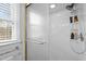 White-tiled stand up shower stall with glass door, window, and storage at 7904 Kingsland Dr, Raleigh, NC 27613