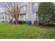 Grassy backyard with deck, steps and trees surrounding townhome exteriors at 8310 Hempshire Pl # 106, Raleigh, NC 27613