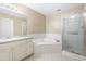 Bright bathroom featuring a soaking tub, glass shower, and single sink vanity with storage at 8310 Hempshire Pl # 106, Raleigh, NC 27613