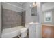 Standard bathroom with gray tiled shower, white vanity and toilet, and a view to an adjacent bedroom at 907 Holloway St, Durham, NC 27701