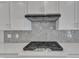 Close-up showcasing sleek gas range with modern vent hood and stylish backsplash at 9168 Dupree Meadow Dr # 15, Angier, NC 27501