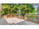 Exterior view of a home featuring a spacious wooden back deck with railings surrounded by green trees at 98 Beach Ln, Henderson, NC 27537