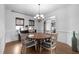 Bright dining room features wood floors, round table, stylish chandelier, and natural light from the window at 1009 Bexley Hills Bnd, Apex, NC 27502