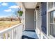 Inviting covered porch with blue flooring, white railings, and a hanging flower basket next to the front door at 1033 Forest Glen Dr, Raleigh, NC 27603