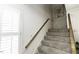 Carpeted staircase featuring neutral tones and a wooden handrail, leading to the next level at 104 Province Cir, Rocky Mount, NC 27804