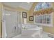 Bright bathroom boasts a walk-in shower, bathtub with jets, and a large window letting in natural light at 106 Legault Dr, Cary, NC 27513