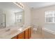 Bathroom featuring double sinks, a large mirror, tub, and tile flooring at 110 Darley Dale Loop, Apex, NC 27502